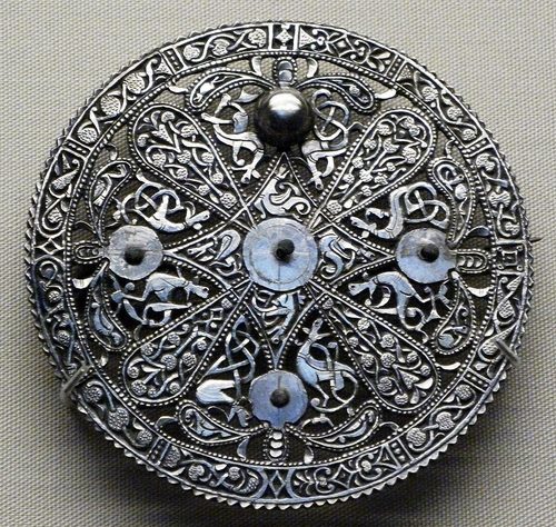 A scalloped-edged Pentney brooch with beaded borders and a four-lobed centre. British Museum.