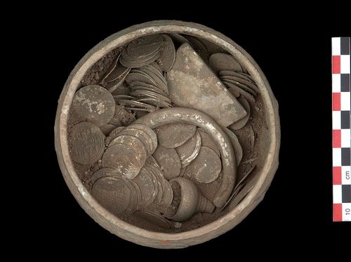 The cup during micro-excavation, still packed with coins and silver.