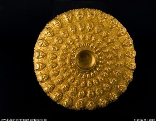 The gold phiale, covered in rings of embossed heads and acorns.