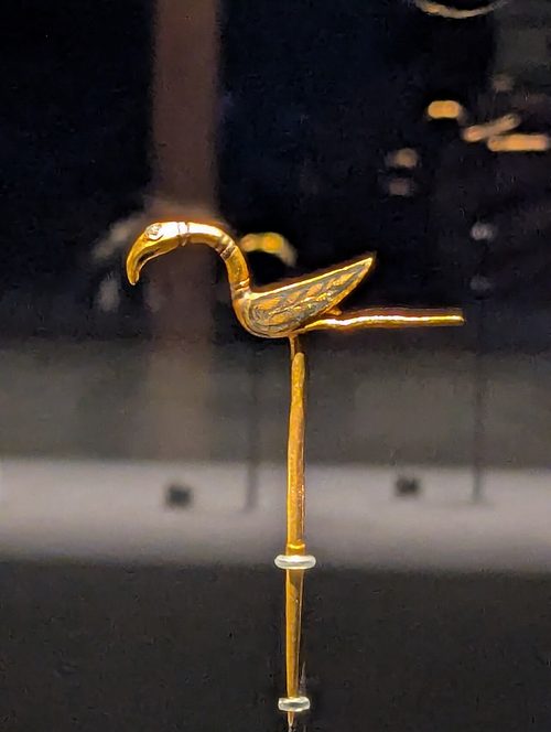 The gold bird-headed pin found inside the arm-ring cluster.
