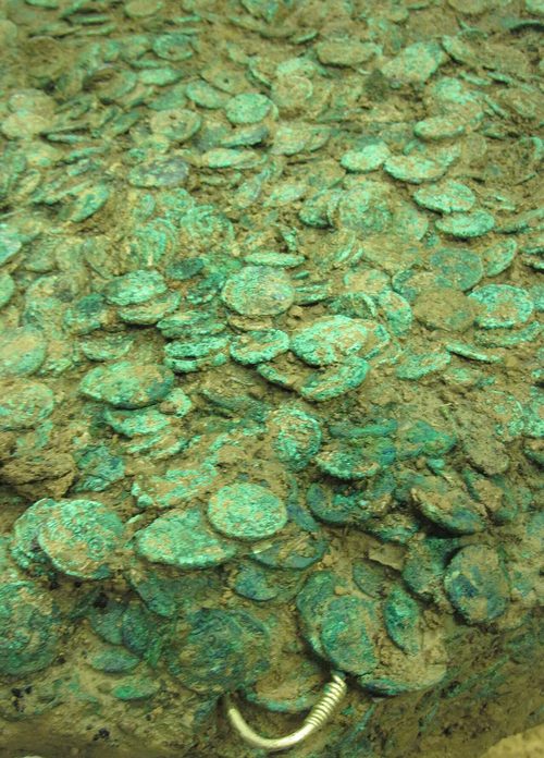 The excavated block under cleaning, with jewellery protruding from the coins.