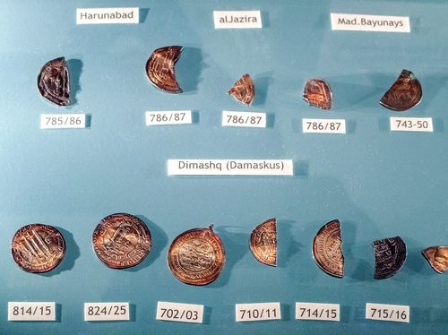 Whole and cut dirhams from the Spillings Hoard displayed with their mints and dates, including Damascus.