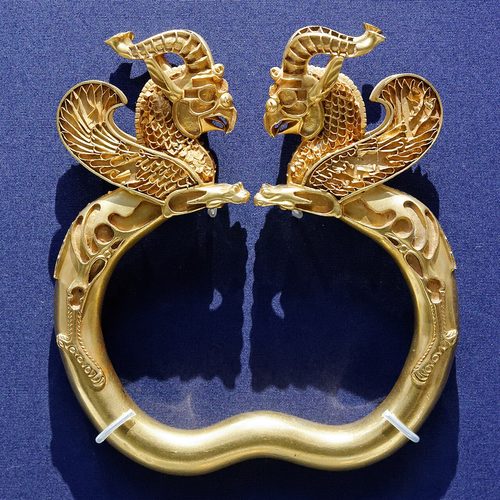 Gold armlet with griffin terminals, one of a pair; its inlays are lost.